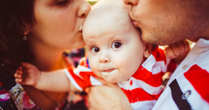 man and woman kissing baby on forehead