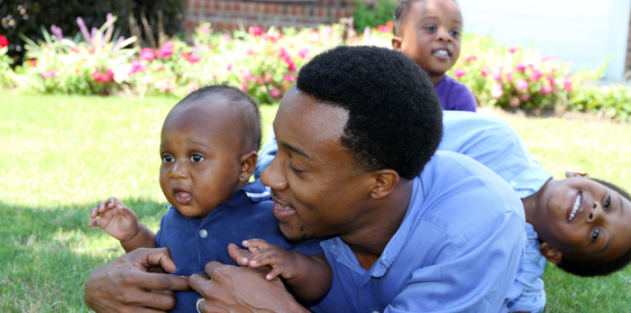 man holding baby boy with two young boys in background