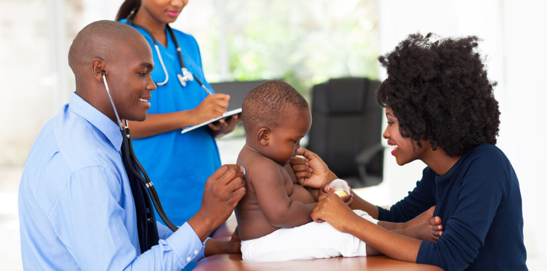 male health care professional, female health care professional, woman, and baby on exam table