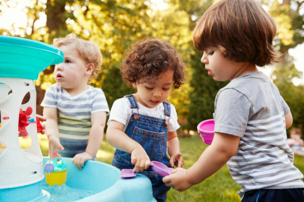 Three toddlers playing at a water table