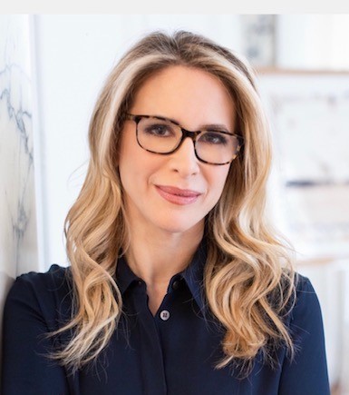 woman with blonde hair and glasses smiling at camera