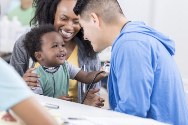 male medical professional with woman and toddler hold a stethoscope