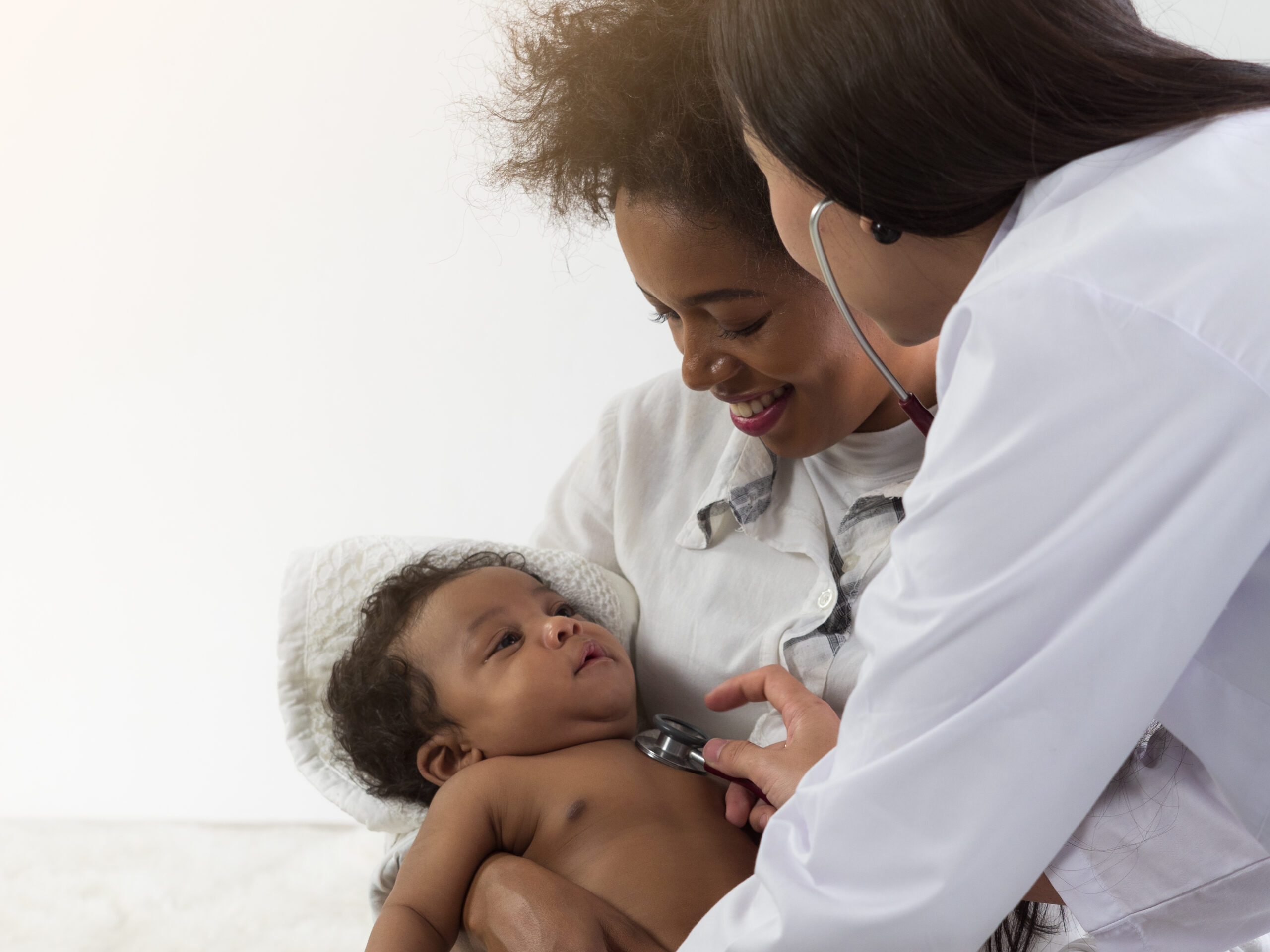 health care provider holding stethoscope to baby being held by woman