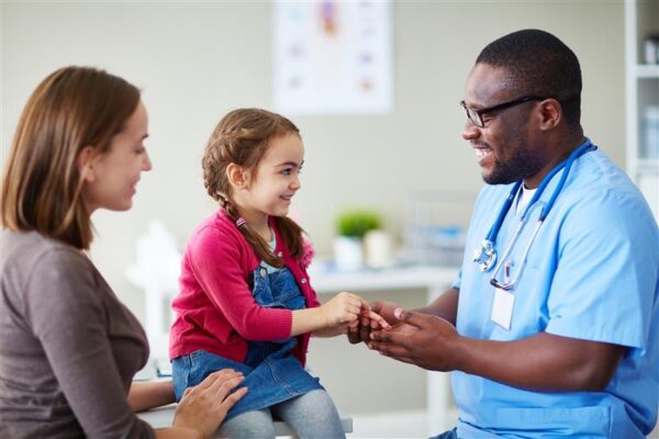 doctor interacting with a young children and mother in a doctor's office