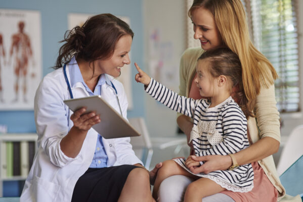 woman and young child with health professional in exam room