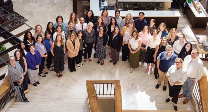 A large group of people standing on a staircase and smiling up at a camera