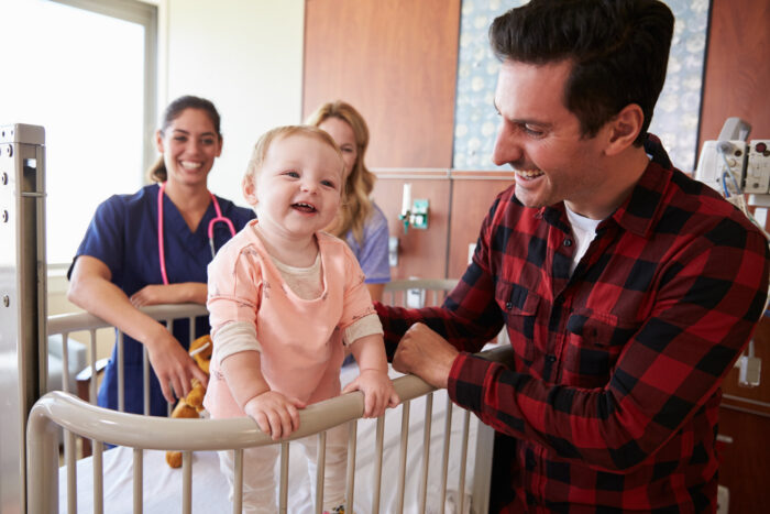 Family with young baby and medical professional in exam room