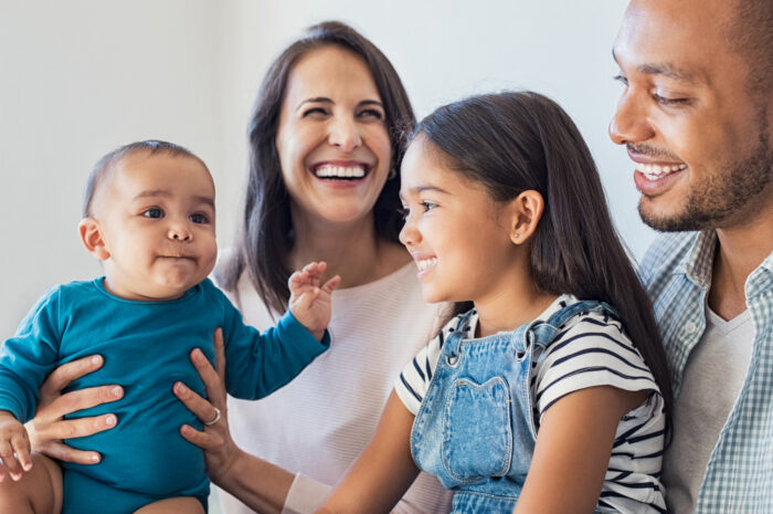 family sitting and smiling with mom, dad, baby, and toddler