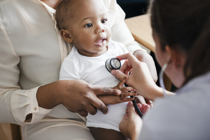 Medical professional holding stethoscope to baby's chest