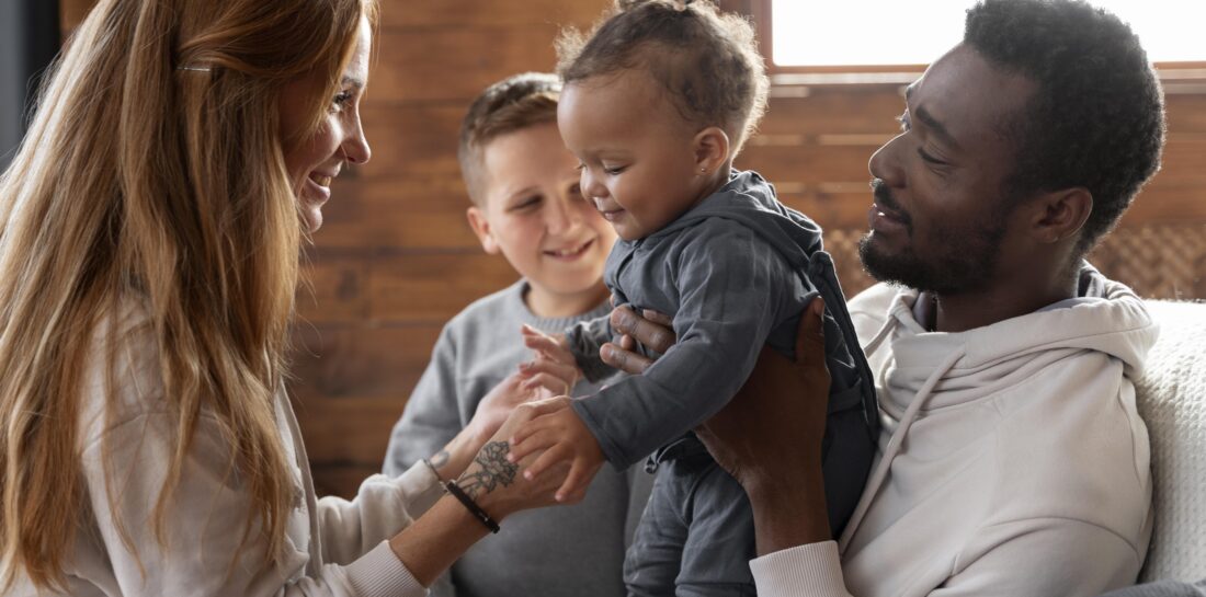 Parents holding toddler with young child in background