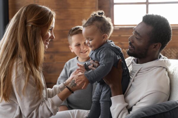 Parents holding toddler with young child in background